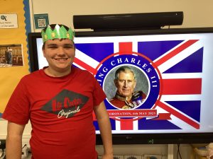 Boy wearing crown in front of picture of King Charles